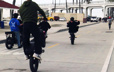 Three people on e-bikes riding on street