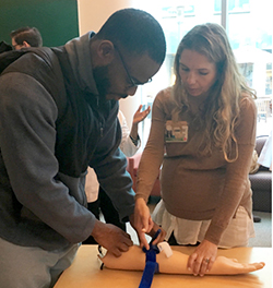 Dr. Amelia Simpson teaches 3rd year medical school student, Ou Akinrimisi, how to use a tourniqet.